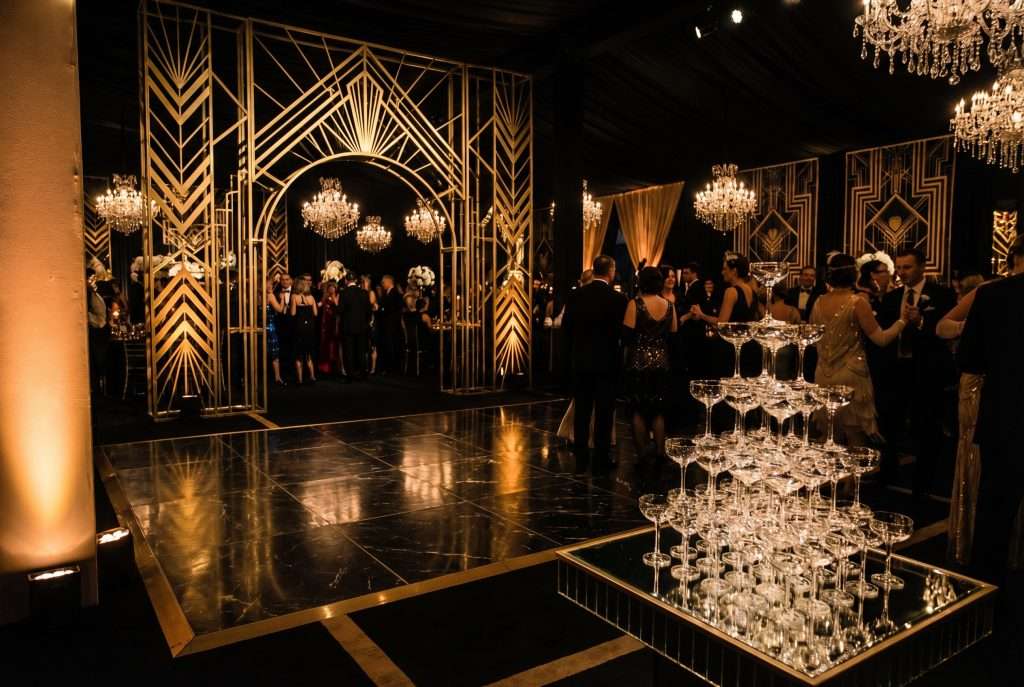 Jet Noir wedding ballroom with a geometric gold archway and a champagne tower on the dance floor