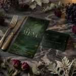 Enchanted Forest menu card and place card set at a stone table with gold cutlery, dark roses and dusty miller