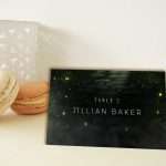 Enchanted Forest place card in full woodland artwork, propped against macarons at a place setting