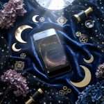 Midnight Celestial wedding invitation on a phone screen on navy velvet, with a brass telescope, dried hydrangea and gold moons