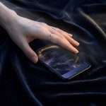 A hand resting on a phone showing the Midnight Celestial thank you, on navy velvet