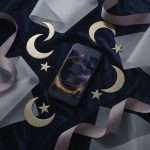 Midnight Celestial thank you on a phone screen among gold crescent moons and stars on grey silk