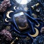 Midnight Celestial thank you on a phone screen on navy velvet, with a brass telescope and dried hydrangea