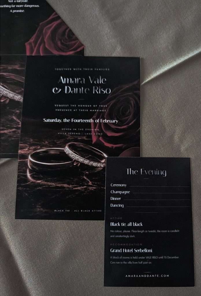 Obsidian Vow Rose suite wedding invitation with two rings beside a red rose on dark marble, photographed next to the evening details card.