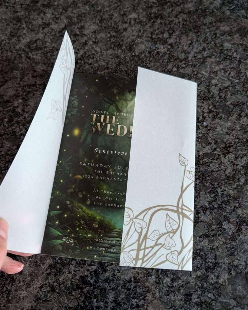Hand opening a hand-drawn ivy vellum wrap over an Enchanted Forest wedding invitation
