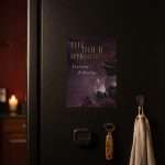 Dark Romance 5x7 save the date magnet on a dark fridge in a candlelit kitchen, a linen towel hanging beside it