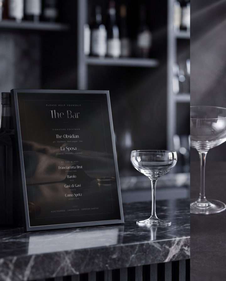 A dark bar menu card in smoke black and gunmetal, two signature cocktails and four by the glass
