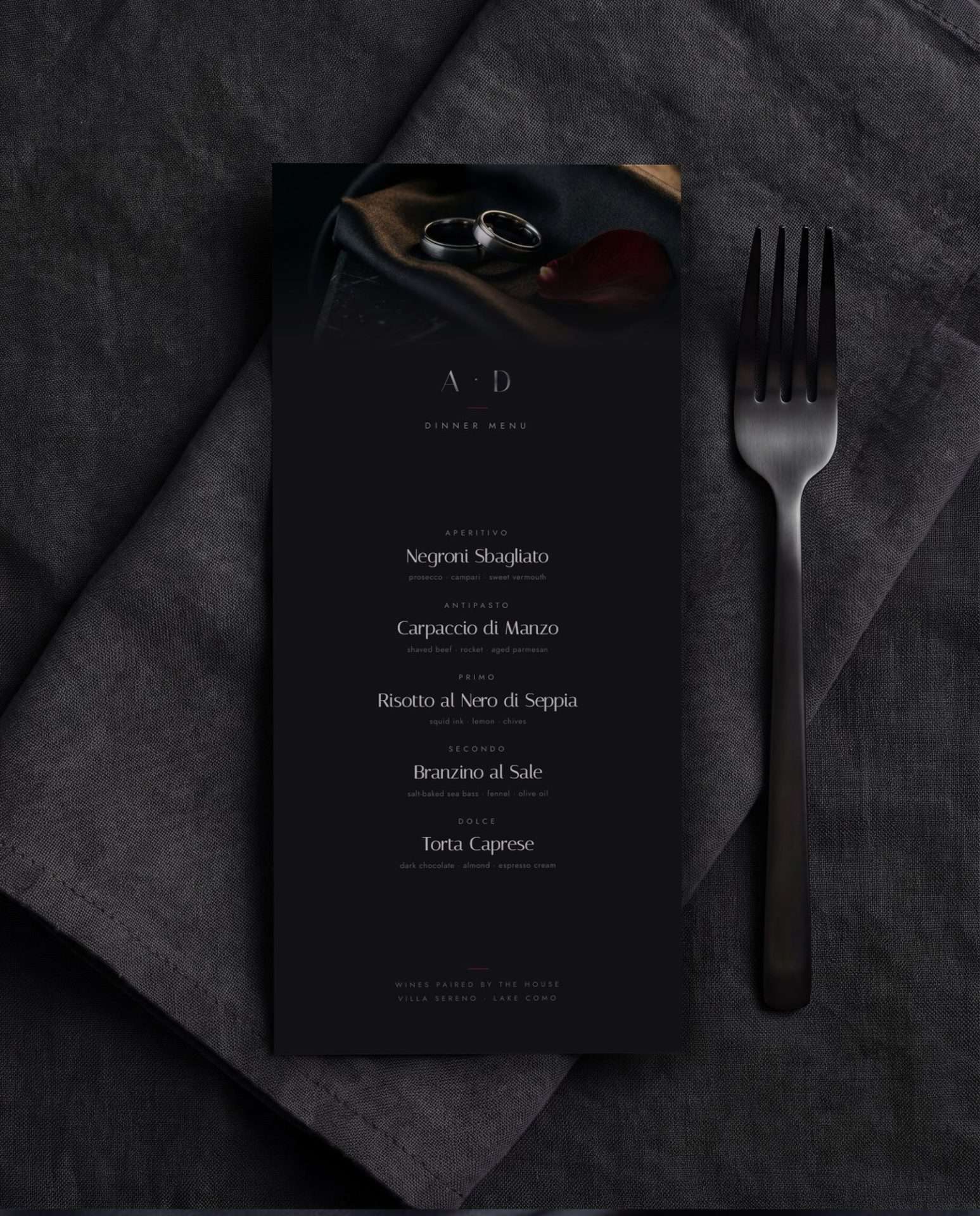 A dark dinner menu card set in gunmetal type against a smoke black ground
