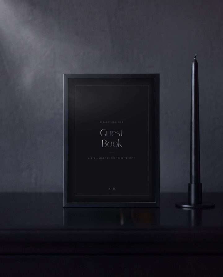 The Obsidian Vow guest book sign in a black frame on a dark sideboard, a black taper candle beside it