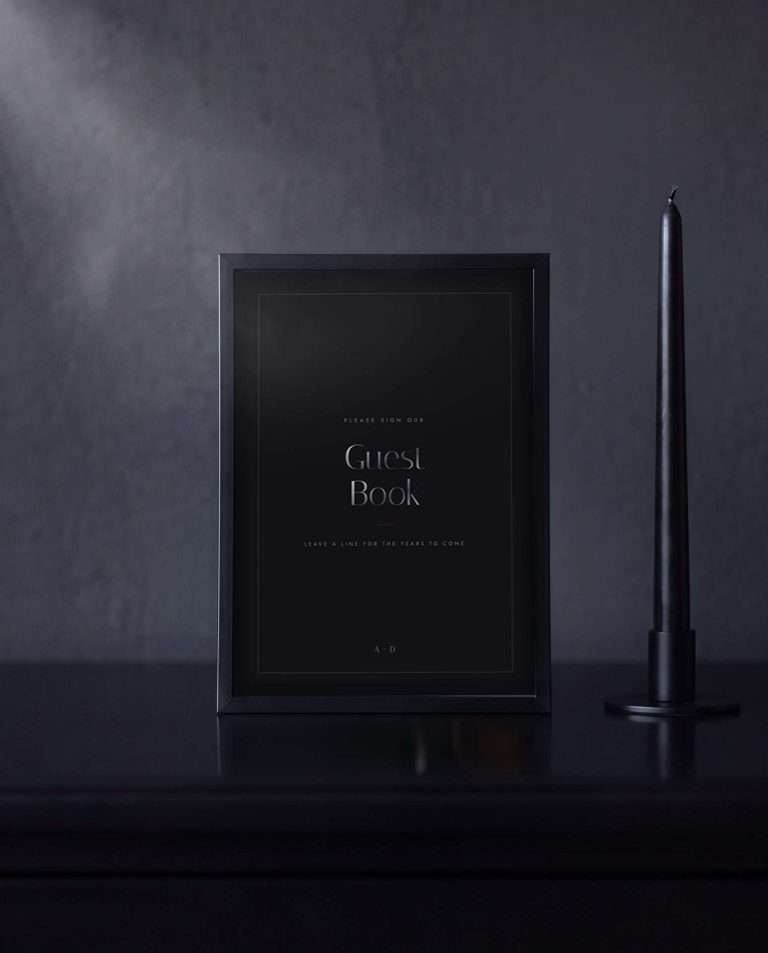 The Obsidian Vow guest book sign in a black frame on a dark sideboard, a black taper candle beside it