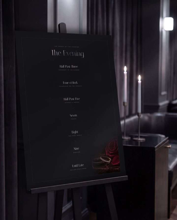 The 18 by 24 Obsidian Vow Order of the Evening sign on a black easel in a candlelit room, the timeline of the night set down its centre