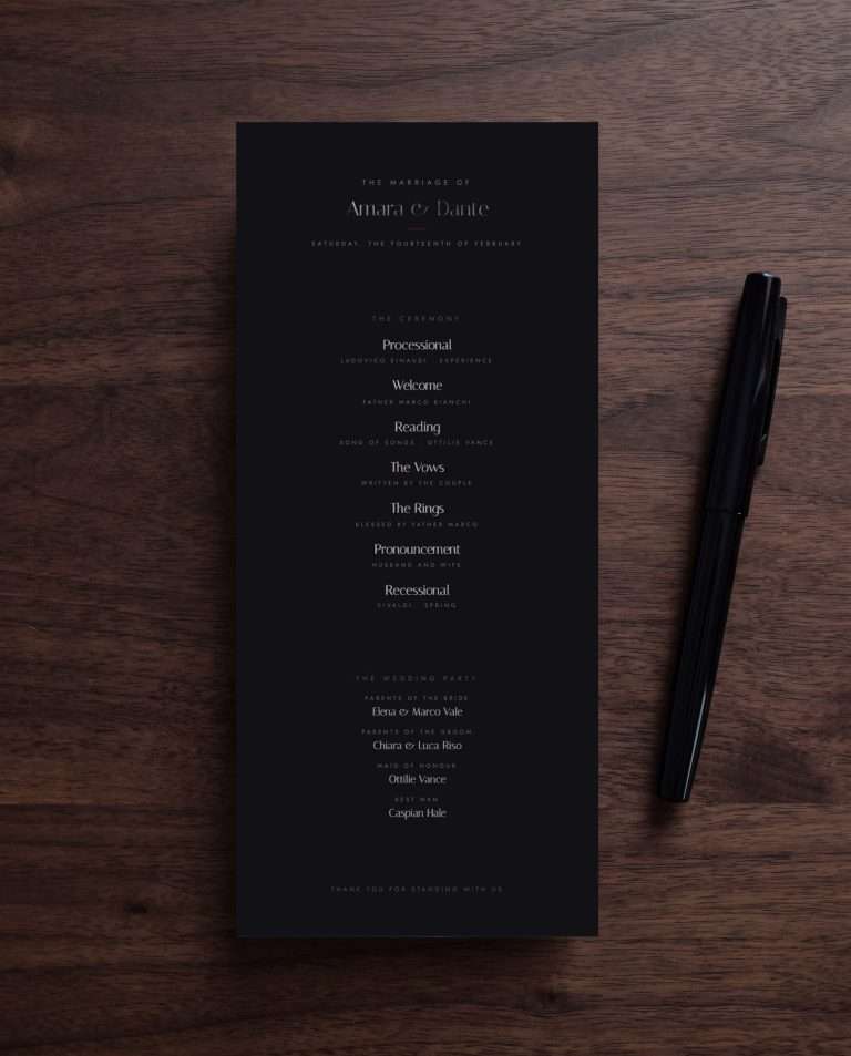 The Obsidian Vow ceremony program on dark wood, the order of ceremony set in gunmetal, a black pen beside it