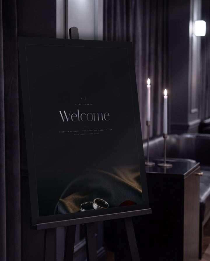 The 18 by 24 framed Obsidian Vow welcome sign on an easel, candlelight and dark drapery behind it
